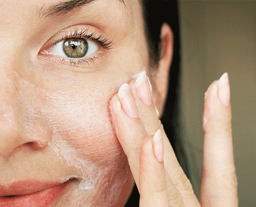 Kobieta aplikuje krem na łuszczącą się skórę na twarzy